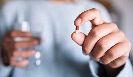 medication - person holds pill and glass of water